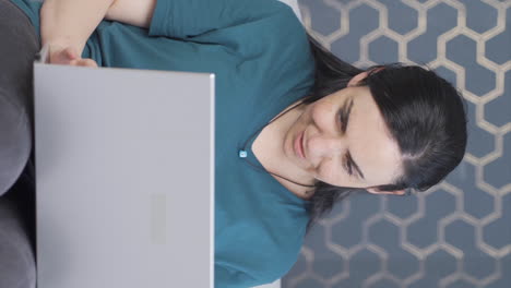 Vertical-video-of-Woman-watching-movie-on-laptop-with-happy-expression.